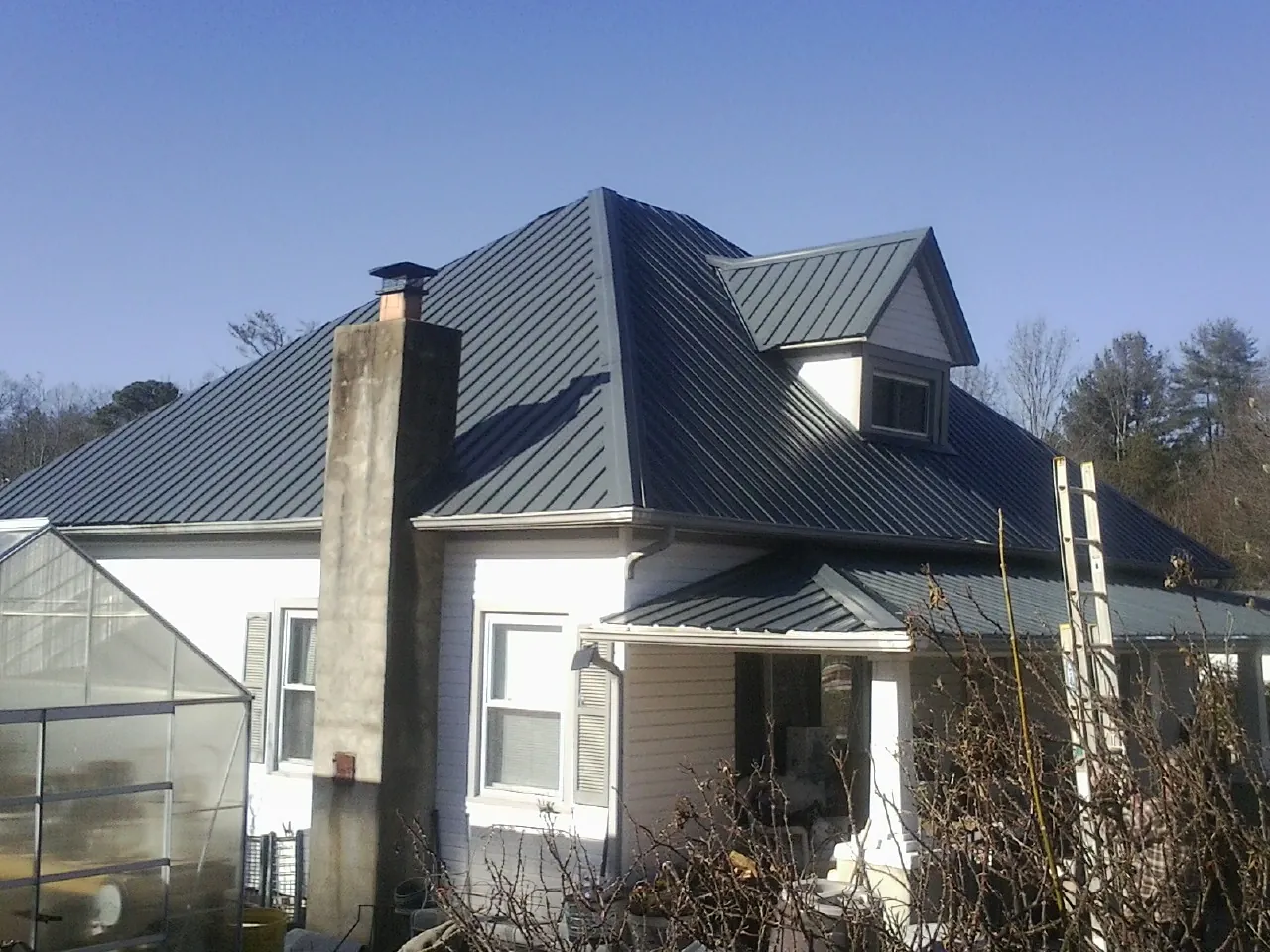 Dark blue standing seam metal roof on a white farmhouse with dormer — Slate & Tile Roof Repair by Roofing Brothers in Blauvelt