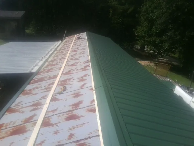 Old rusted panels beside newly installed green metal roofing — Wind Damage Roof Repair by Roofing Brothers in Blauvelt