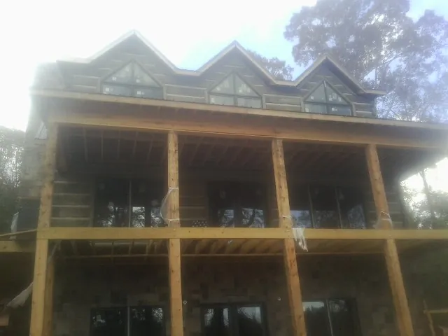Dormers and porch framing on a large log home under construction — Roof Coating work by our crew in Blauvelt