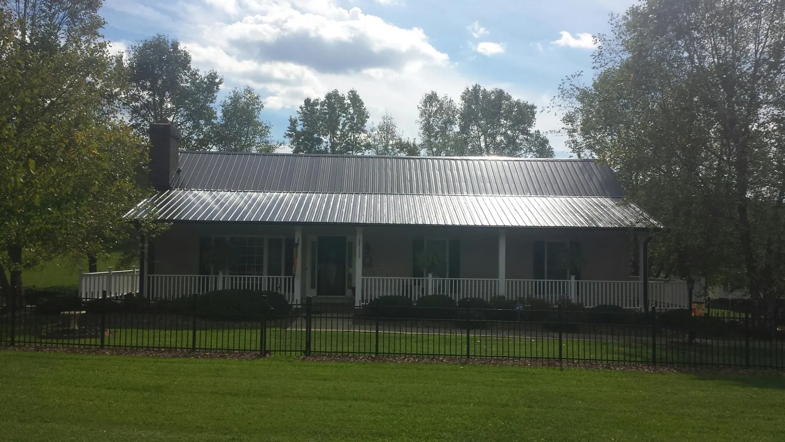 Gray metal roof on a brick ranch with a full width front porch — Gutter Guard Installation work by our crew in Blauvelt