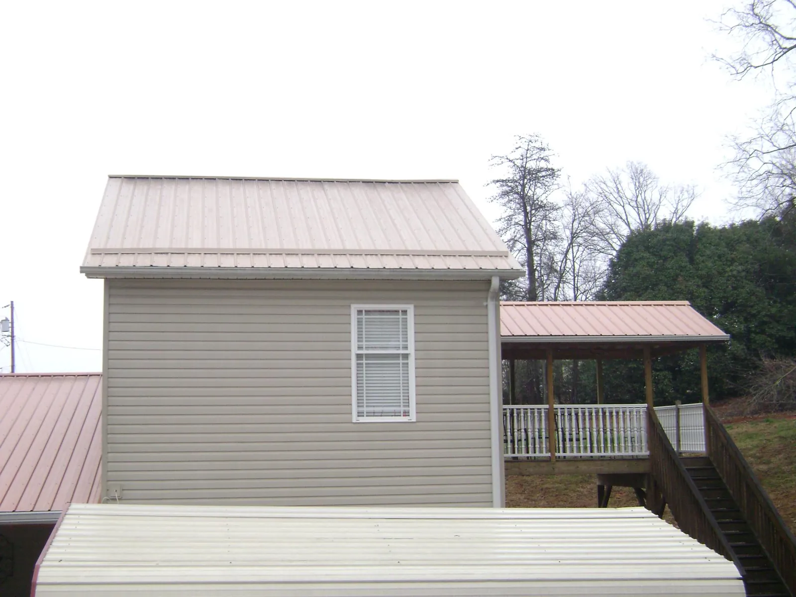 Tan metal roofs on a two story addition and attached porch, from a Roof Replacement job in Blauvelt