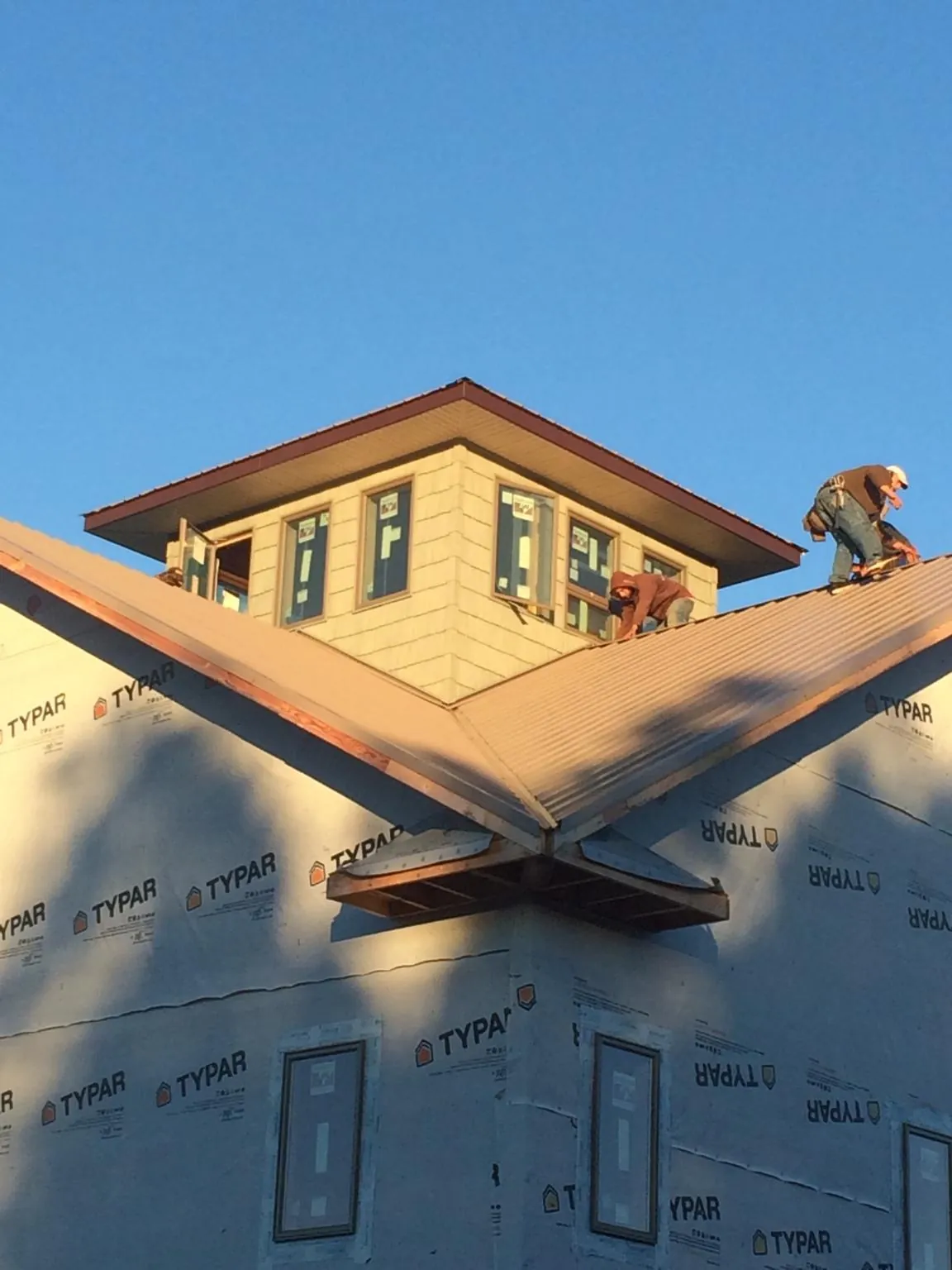 Roofers working around a rooftop cupola on a new metal roof at sunset — Roof Waterproofing in Blauvelt by Roofing Brothers